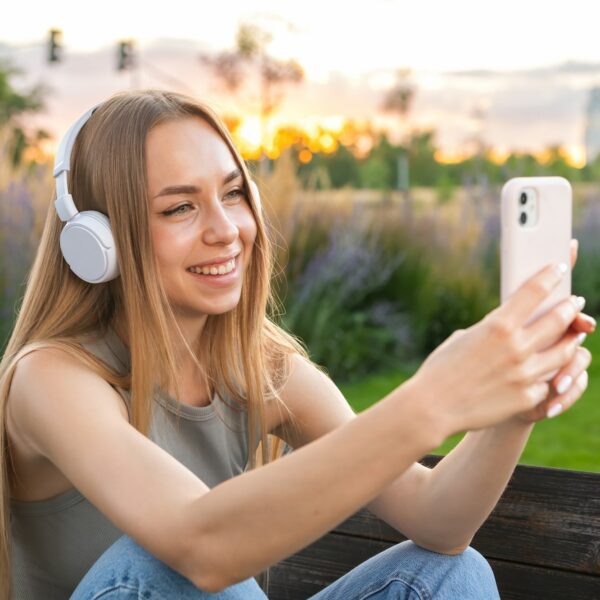 Blonde blogger shoots storytelling sitting in the park on the bench.